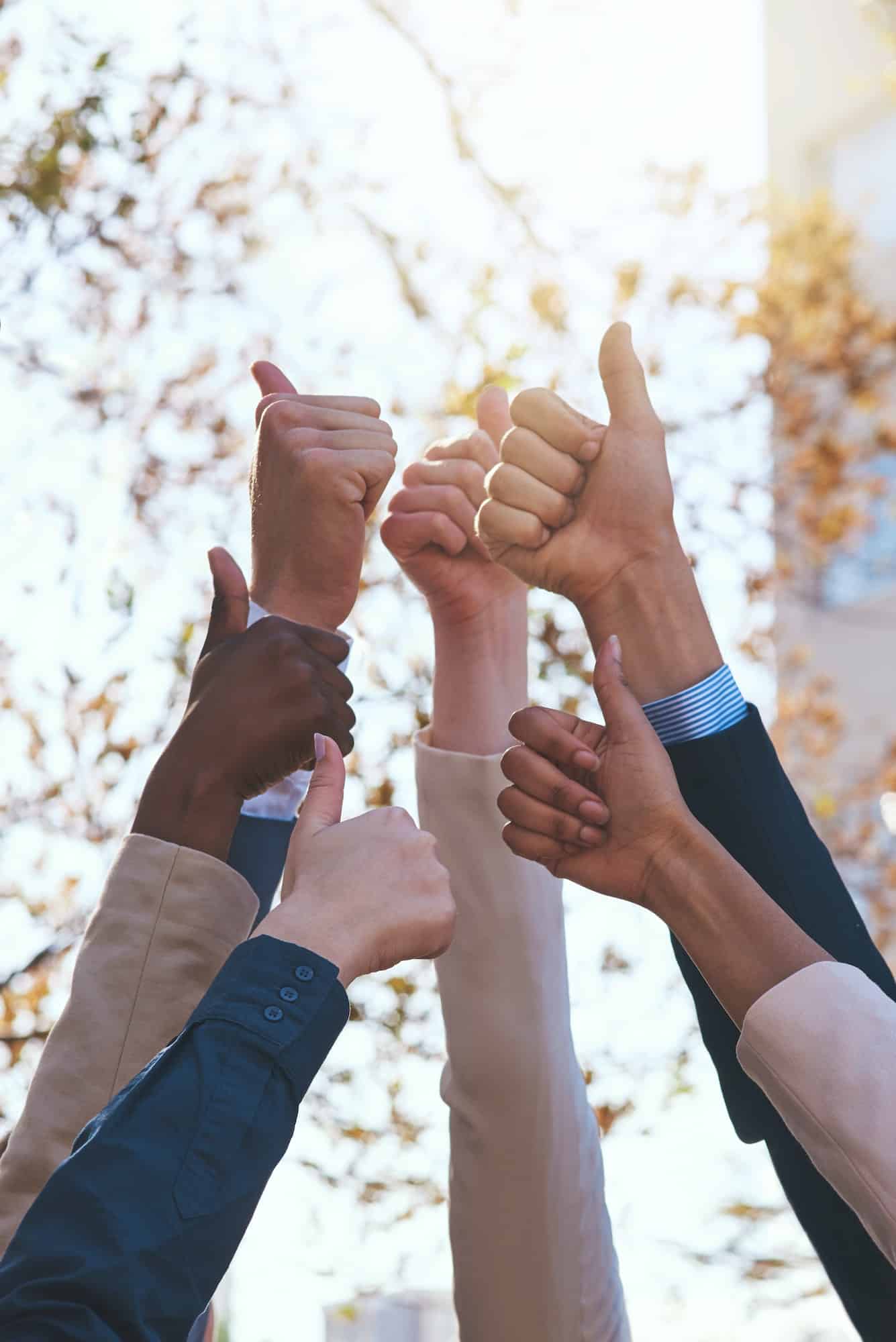 Excellent. Cropped shot of a group of hands showing thumbs up.