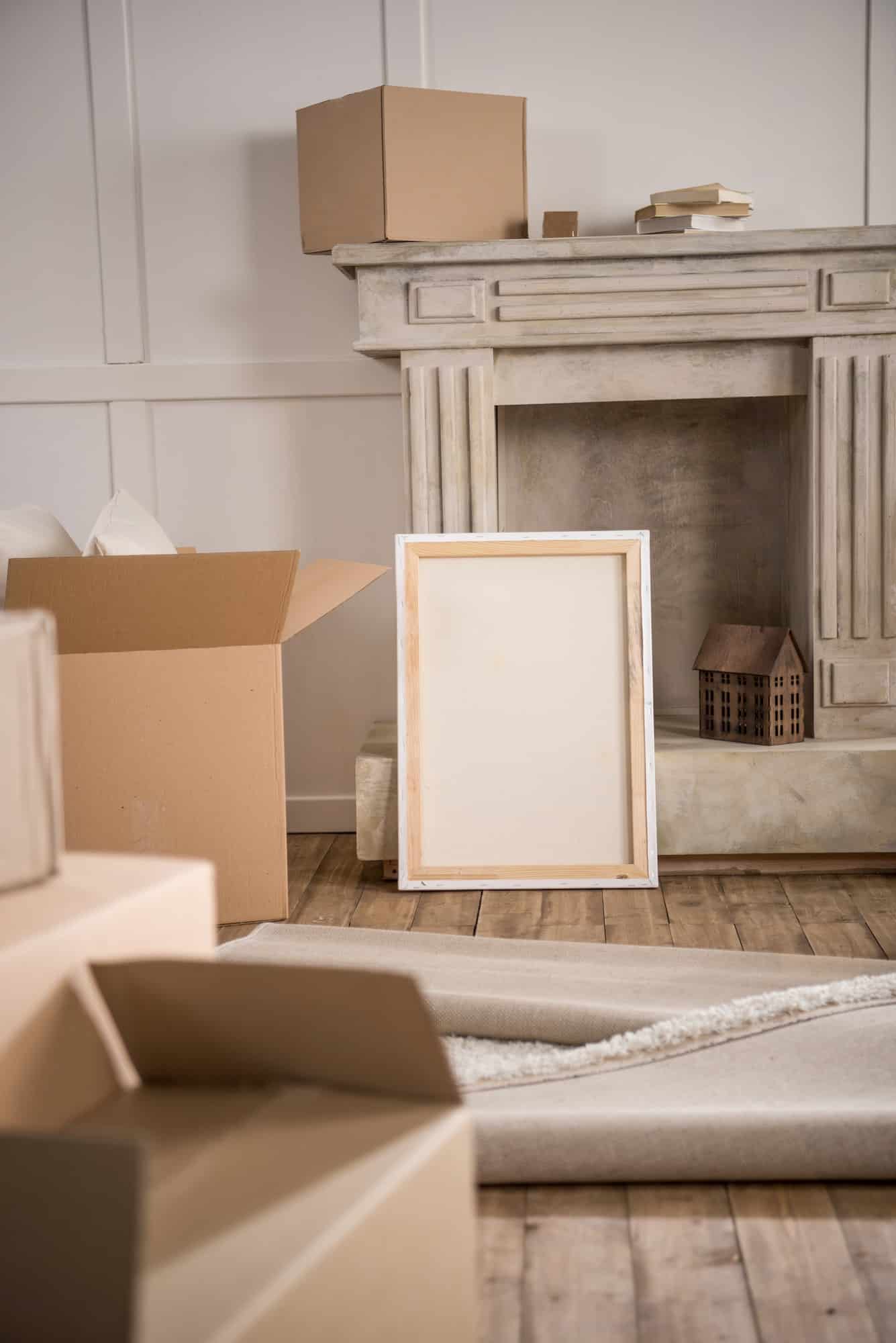 Picture frame and cardboard boxes in empty room, relocation concept
